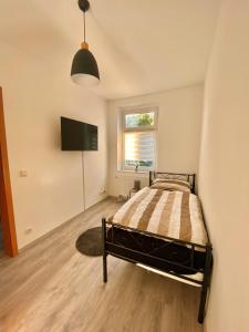 Schlafzimmer mit einem Bett und einem Flachbild-TV in der Unterkunft Gemütliche 3-Zimmer Ferienwohnung in Leipzig 1 OG in Leipzig