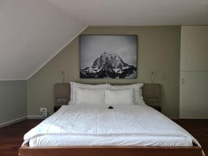 - une chambre dotée d'un grand lit blanc avec une photo sur le mur dans l'établissement Lucerne Lake View Apartments, à Lucerne