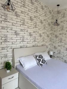 a bed with two pillows and a brick wall at Boutique Room in Koregaon Park. WiFi, Ac, Smart Tv in Pune +4 photos