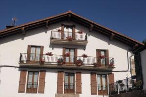 um edifício branco com varandas e flores em Gartzinea, amplia y preciosa vivienda rural em Ezkurra