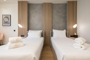 two beds in a room with white sheets and towels at GRAND PATELLI in Myrina