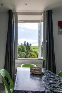 a dining room with a table and a large window at LA BATISSE l'arbre gris in Le Grand-Abergement