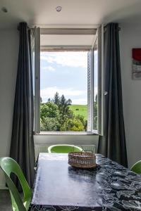 a dining room with a table and a large window at LA BÂTISSE l'arbre gris in Le Grand-Abergement