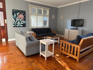 ein Wohnzimmer mit einem Sofa, Stühlen und einem TV in der Unterkunft The Owl on 5th in Port Elizabeth