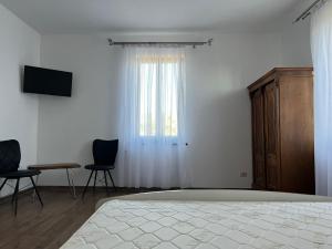 a bedroom with a bed and two chairs and a window at Pensiunea La Conac in Bîrlad