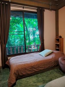 - une chambre avec un lit et une grande fenêtre dans l'établissement Oldy De Garden, à Chiang Mai