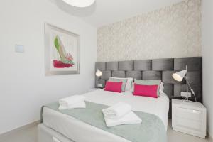 um quarto com uma cama grande e almofadas cor-de-rosa e verde em Luxury Duplex Penthouse with sea views walking distance to the beach in Los Miradores del Sol em Estepona