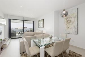 uma sala de jantar com uma mesa de vidro e cadeiras brancas em Luxury Duplex Penthouse with sea views walking distance to the beach in Los Miradores del Sol em Estepona
