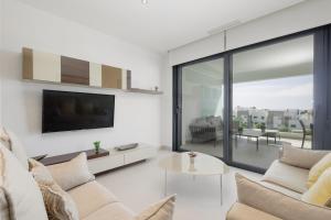 uma sala de estar com um sofá e uma televisão em Luxury Duplex Penthouse with sea views walking distance to the beach in Los Miradores del Sol em Estepona