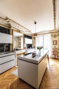 a large kitchen with white counters and a large island at Veeve - Classical Features in the 9th in Paris
