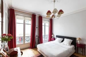 a bedroom with a large bed with red curtains at Veeve - Classical Features in the 9th in Paris
