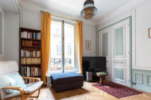 a living room with a tv and a window at Veeve - Classical Features in the 9th in Paris