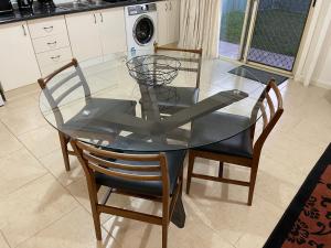a glass dining room table with two chairs and a kitchen at Comfortable and well equipped Studio Apartment in Mudgee - Rest Easy Mudgee Studio in Mudgee +2 photos