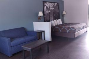 sala de estar con sofá y cama en Super 8 Motel by Wyndham near Fort Lauderdale Arpt, en Dania Beach