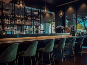 a bar with green chairs and a bar counter at Novotel Melbourne Glen Waverley in Glen Waverley