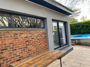 a wooden bench sitting in front of a brick wall at 46 on Allcock Guest Apartment & Luxury Room in Pretoria