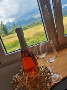- une bouteille de vin et deux verres devant une fenêtre dans l'établissement Domčok pod Tatrami, à Važec