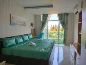 - une chambre avec un lit vert et une grande fenêtre dans l'établissement Căn hộ view biển Sea Links MŨI NÉ, à Phan Thiết