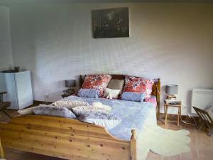 ein Schlafzimmer mit einem Holzbett mit Kissen darauf in der Unterkunft Chez Tobi in Bazincourt-sur-Epte