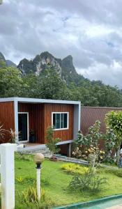 a small house with a mountain in the background at 99 Camp and Cafe in Khao Sok