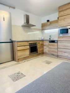 eine Küche mit Holzschränken und einem Kühlschrank aus Edelstahl in der Unterkunft Con vistas al mar y PortAventura in Salou