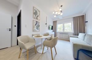 uma sala de estar com um sofá, uma mesa e cadeiras em Apartament na Grochowej Centrum NOWOŚĆ em Bialystok