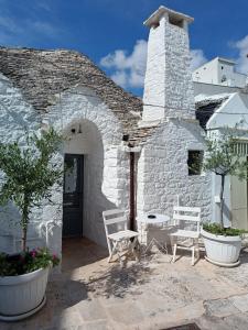 Maison en pierre avec 2 chaises et une table dans l'établissement Trulli D'Angiò, à Alberobello