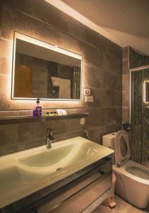 een badkamer met een wastafel, een spiegel en een toilet bij The Row Residential Hotel in Addis Ababa