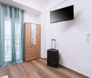 Zimmer mit Koffer und TV an der Wand in der Unterkunft Sifogiannis Rooms in Kamilari