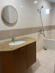 a bathroom with a sink and a shower with a mirror at Santubong Suites Lower Level in Kuching