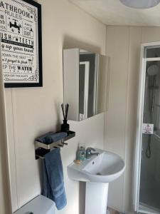a white bathroom with a sink and a mirror at Lovely 2-Bed Cabin in Birchington in Birchington