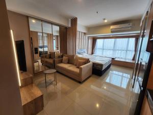 een woonkamer met een bank en een bed bij Irvine Suites Lantai 26-I2618 in Cikarang