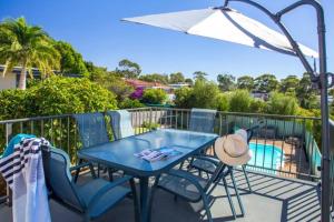 a blue table and chairs on a balcony with a pool at Modern Farmhouse at Pacific Sands Mollymook Beach in Mollymook