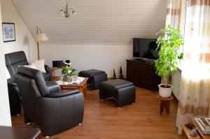 a living room with black leather chairs and a flat screen tv at Hortensie, Ferienwohnung in Schneverdingen