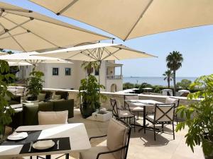 restauracja z białymi stołami, krzesłami i parasolami w obiekcie Grande Real Villa Itália Hotel & Spa w mieście Cascais