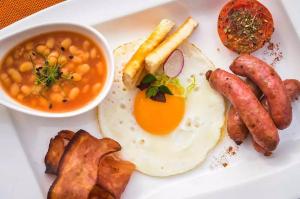 a plate of breakfast food with eggs sausage and beans at Grande Real Villa Itália Hotel & Spa in Cascais