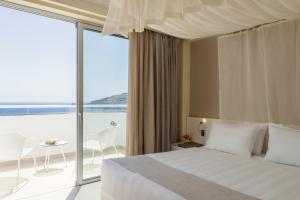 a bedroom with a bed and a view of the ocean at Lindos Village Resort & Spa - Adults Only in Líndos