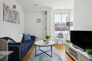a living room with a blue couch and a tv at Luxury Urban Living - 1 BDR in London