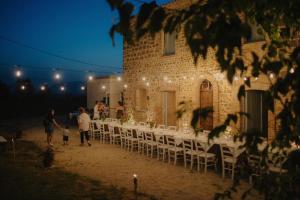 a group of people standing outside of a building with tables and chairs at Arcadia Agriturismo in San Nicola Manfredi