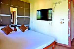 a bedroom with a bed with a tv on the wall at Hulihara Homestay - Full Villa, Coffee Estate & Balcony View in Sakleshpur