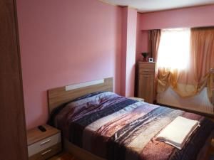 a bedroom with a bed with pink walls and a window at Apartaments Viktoria in Silistra