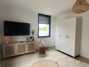a living room with a television and a white cabinet at Boho Appartement in Bielefeld