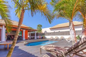 a villa with a swimming pool and palm trees at Villa Loira in Corralejo