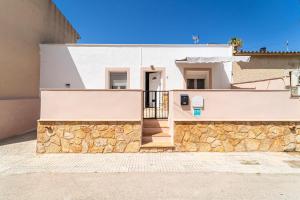 uma casa branca com uma parede de pedra em Townhouse Forteza By homevillas360 em Colonia de Sant Pere