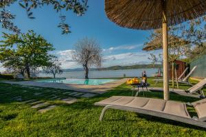 um resort com uma piscina, um banco e um guarda-sol em La Folaga del Trasimeno em Magione