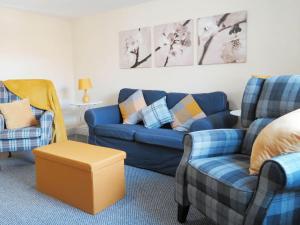 a living room with a blue couch and two chairs at Rose Cottage in Richmond +1 photo