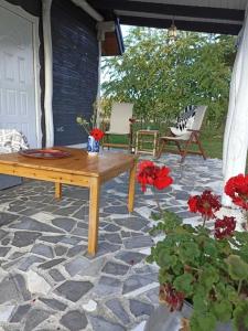 a patio with a wooden table and red flowers at Bajkowy Domek nad rzeką Liwiec in Łochów
