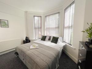 a bedroom with a large bed with two windows at Rock Lane House by Serviced Living Liverpool in Rock Ferry