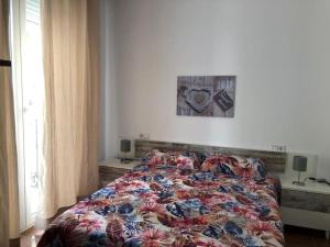 - un lit avec une couette colorée dans une chambre dans l'établissement Bonito apartamento en Calle San Carlos, à Madrid