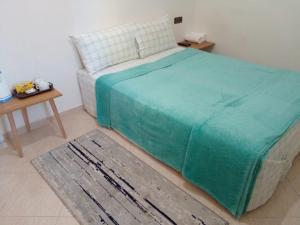 1 dormitorio con 1 cama con manta verde y mesa en Dar Said Airport, en Casablanca
